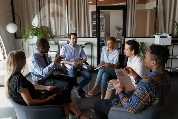 Photo of Multiethnic business team coworkers sitting in circle in office