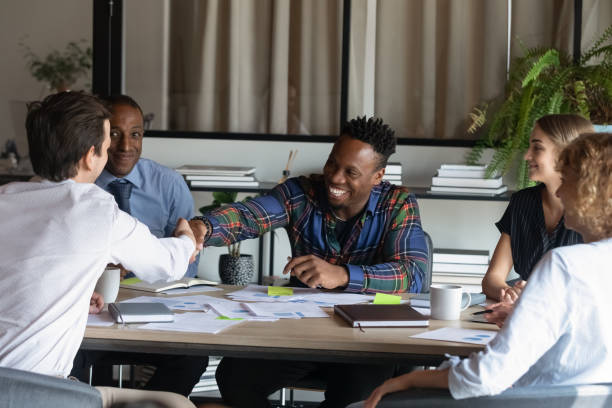 happy multiethnic coworkers shaking hands over table at corporate meeting - locka till kontoret bildbanksfoton och bilder