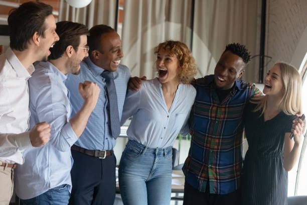 istock Group of happy excited diverse employees hugging, shouting for joy 1395769931