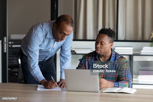 Serious African American Adult Mentor Training Intern At Laptop Stock Photo - Download Image Now