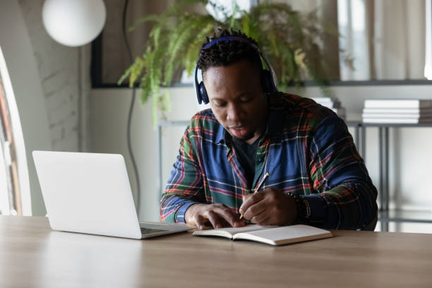 istock Focused serious African American student guy in headphones watching webinar 1395770061