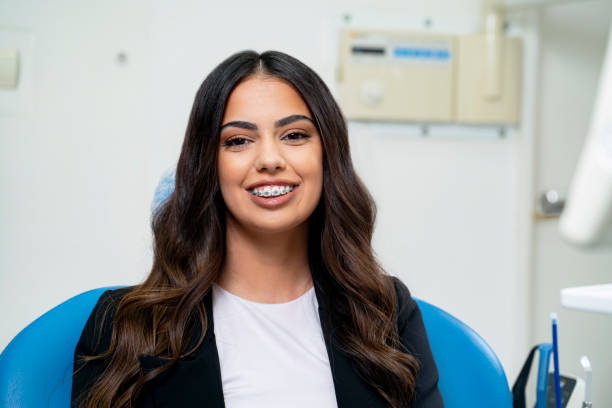 elegante mujer adulta joven sentada en sillón dental, concepto de aparatos dentales - corrector fotografías e imágenes de stock