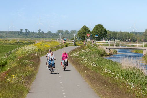 Bunschoten-Spakenburg, Netherlands on May 31, 2021; Three women cycle through the meadows with the colorful wildflowers in the countryside in the spring.