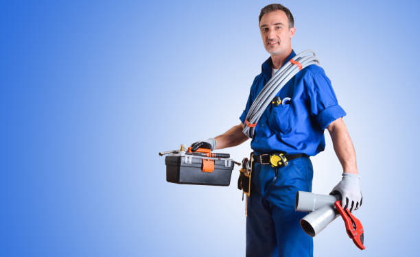 Portrait of uniformed plumber with work tools in hands and blue gradient isolated background. Side view. Horizontal composition.