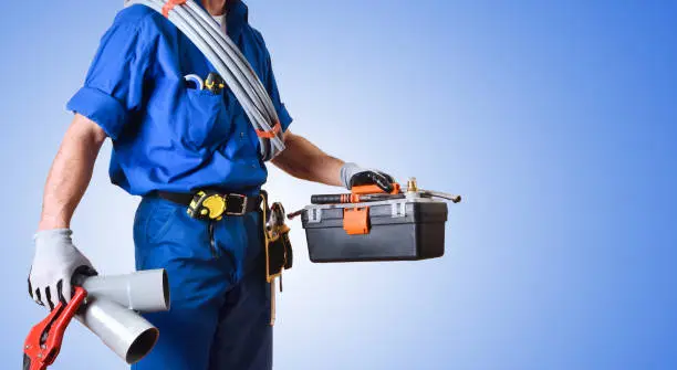 Detail of uniformed plumber with work tools in hands and blue gradient isolated background. Side view. Horizontal composition.