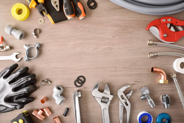 istock Plumbing materials and tools on wooden workbench top view background 1395784007