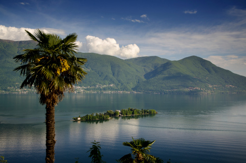 Brissago Islands on Lake Maggiore, surrounded by alpine mountains with blue sky on a beautiful spring day