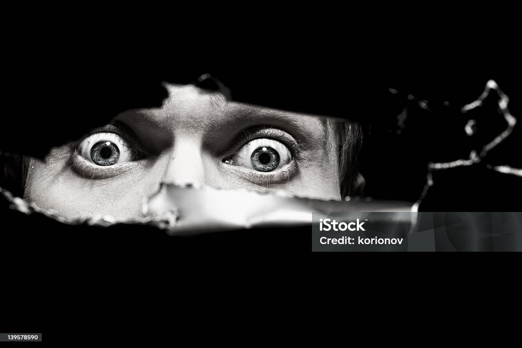 Scary eyes of  man spying through  hole in the wall Scary eyes of a man spying through a hole in the wall close up Adult Stock Photo