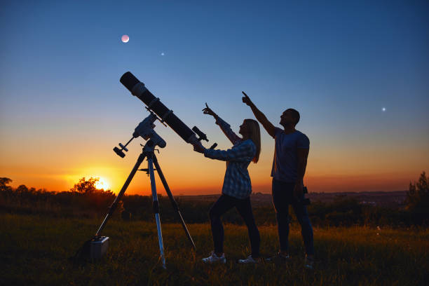 istock Couple stargazing together with a astronomical telescope. 1395787149