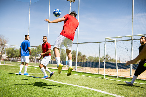 Soccer players jumping to hit the ball with their heads during a corner kick