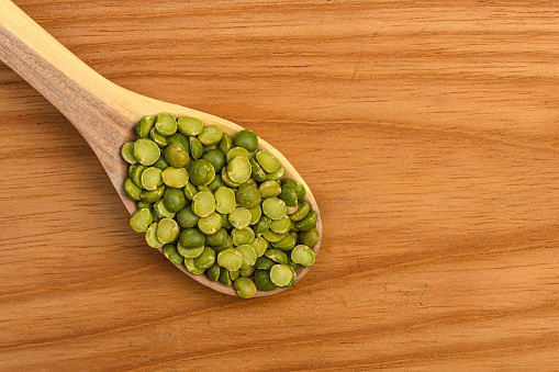 Close up view of split green peas on wooden spoon in the kitchen