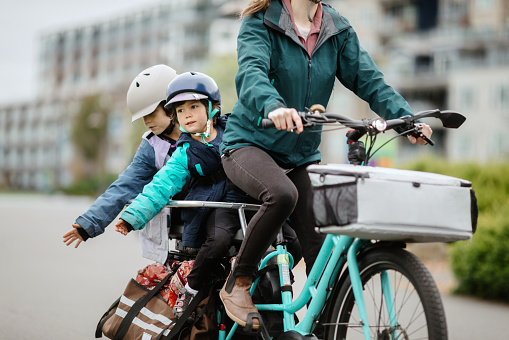 A multiracial family biking on a large electric powered cargo bicycle, perfect for commuting for the environmentally conscious.  Also a fun, healthy family activity that provides good exercise!  Shot in Tacoma, Washington, USA.