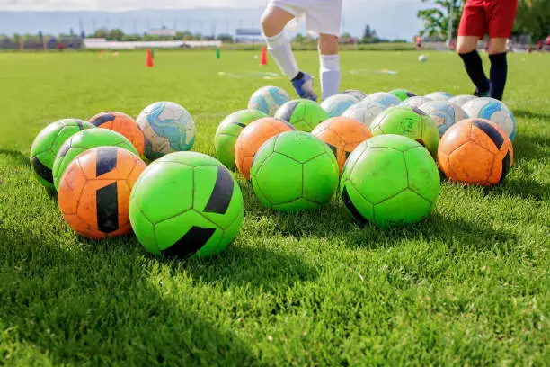 Photo of Soccer gears on green grass prepared for training in kids football academy. Popular sport activity