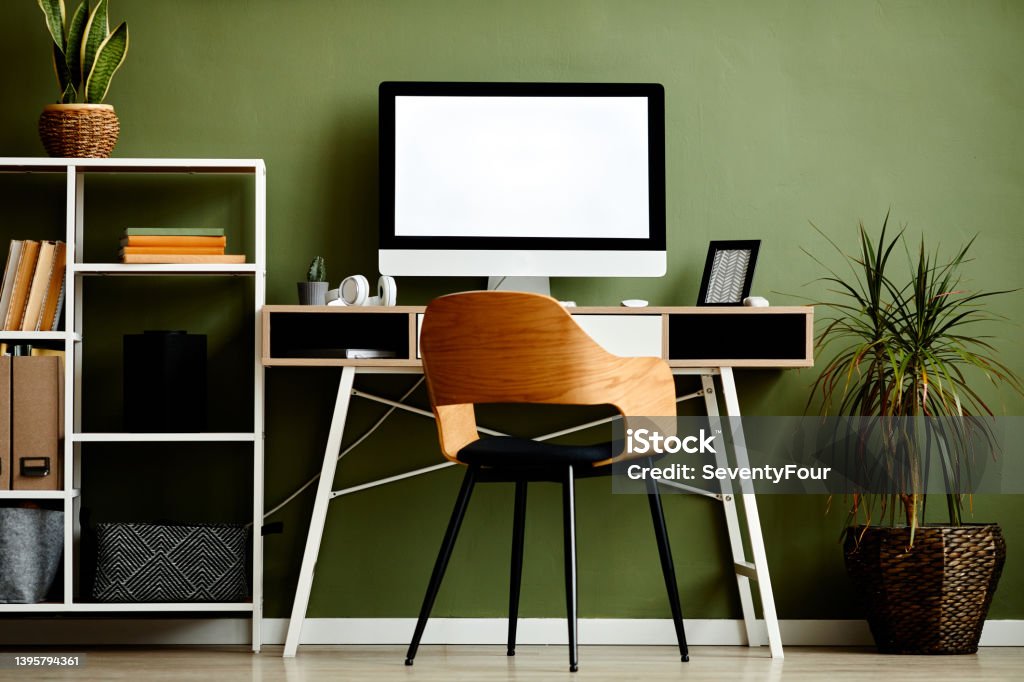 Green Workplace with Computer Mockup Background image of graphic home office workplace with computer on wooden table against green wall, copy space Environmental Conservation Stock Photo