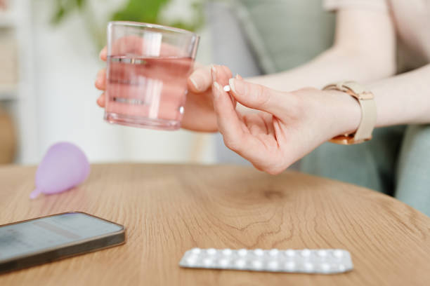 Woman Taking Birth Control Closeup Side view closeup of young woman taking birth control pills with glass of water birth control pill stock pictures, royalty-free photos & images