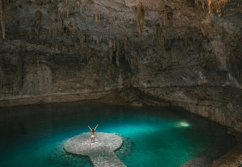 Young Caucasian woman standing in the centre of Cenote in Yucatan, Mexico