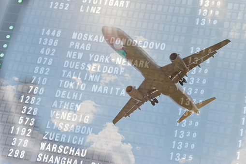 Flying airplane in clouds and arrival departure board with arrival time at Moscow and New York. Double exposure concept.\nThis image is part of an airport series,