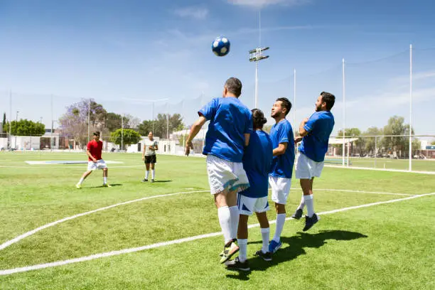 Slow motion video of soccer player free kicking over a defense barrier