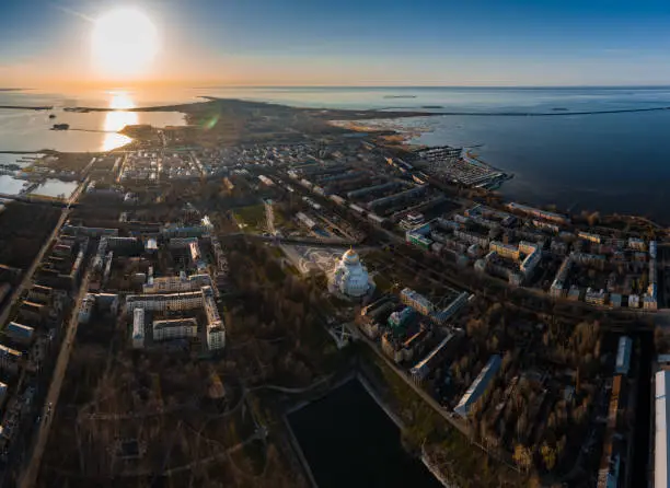 Aerial view of the sea capital of Russia Kronstadt at sunset, the golden dome of the huge main naval cathedral of St. Nicholas, the seaport with warships, dry docks, fortifications with cranes