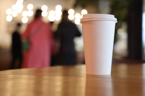 Coffee paper cup on wood table in coffee shop.