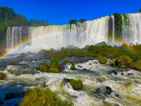 View of the iguazu water falls from the iguaçu river current. Lots of water, green vegetation and the bottom, some water falls.