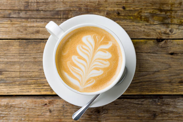 istock coffee cappuccino with pattern on wooden table top view 1395805852