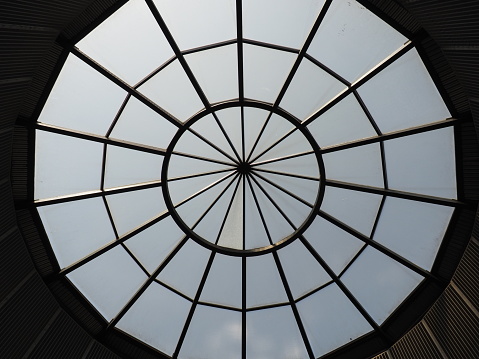 Glass dome or round window in the roof. The sky can be seen through a glass transparent structure in the vault of the building. Architectural fashion motifs in modern construction. A big round window