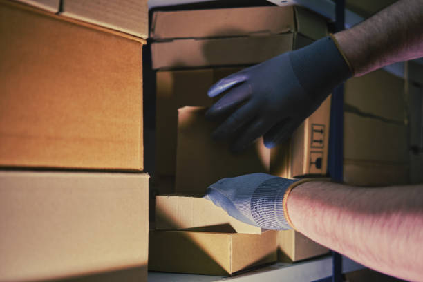 istock A man in gloves steals goods from a box in a warehouse. Problems with theft and security in the office 1395810281
