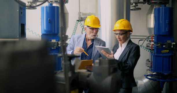 istock Engineers with yellow safety helmets and protective glasses look at a digital tablet. 1395810337