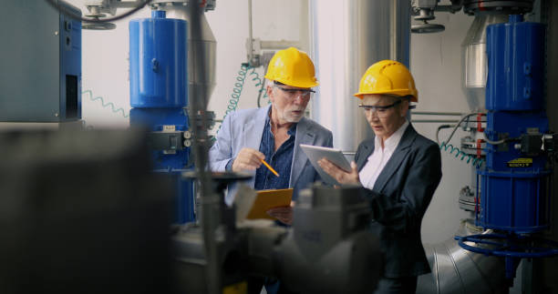 Engineers with yellow safety helmets and protective glasses look at a digital tablet. stock photo