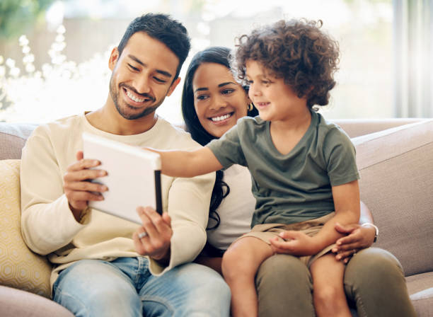 istock Shot of a little boy using a digital tablet while sitting at home with his parents 1395821637