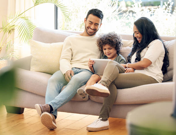 istock Shot of a little boy using a digital tablet while sitting at home with his parents 1395821641