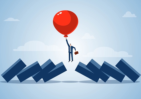 Smart businessman predicts, manages and avoids financial risks, the balloon takes the businessman to fly into the air to avoid dominoes falling to hit the businessman, stop the impact and harm of the economic crisis.