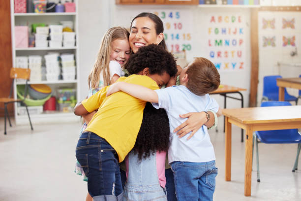 photo d’une femme serrant ses apprenants dans ses bras - child classroom teacher learning photos et images de collection