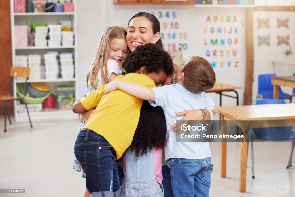 Shot of a woman hugging her learners We love our teacher Teacher Stock Photo