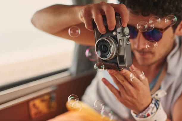 istock Shot of a young man using a camera on a road trip in his van 1395832557