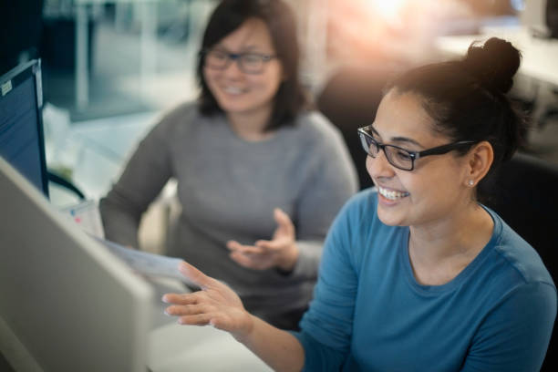 Two woman discussing plans on conference call in office while looking at computer screen