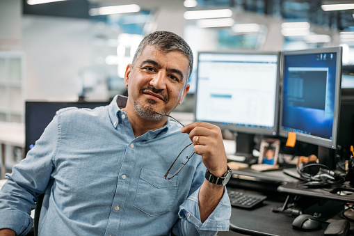 Hombre de negocios asiático de Oriente Medio sentado en la oficina con anteojos y terminal de computadora photo