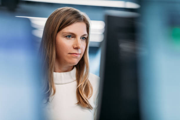 Woman looking at computer monitor in modern office stock photo