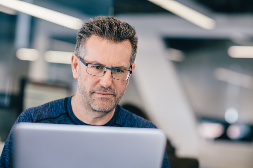 Mature Caucasian man working on laptop in technology office