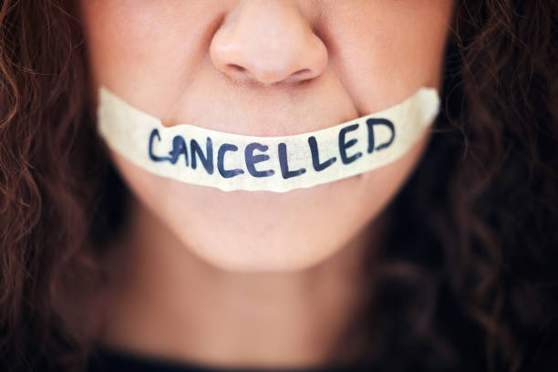 primer plano de una mujer irreconocible con cinta adhesiva en la boca que tiene la palabra "cancelado" escrita en ella - censorship fotografías e imágenes de stock