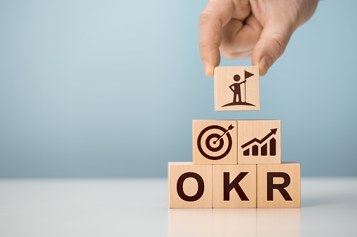 OKR Objectives, Key and Results wooden cube blocks on blue background. Business target and drive business and performance. Business and OKR - objectives and key results concept.