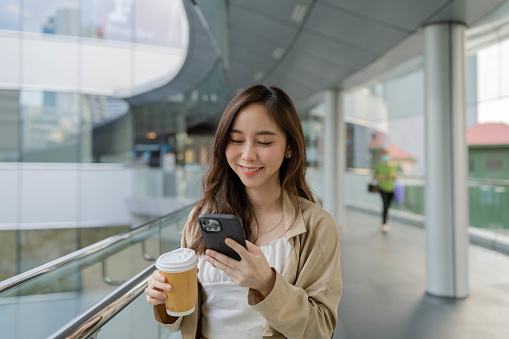 Asian businesswoman using phone while traveling during break