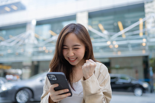 young businesswoman looks at her phone happily after a successful talk with a client.