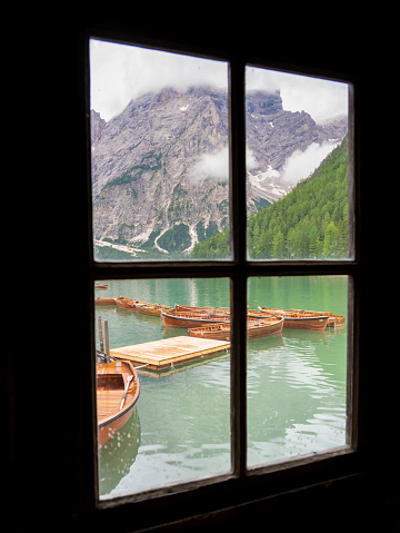 Braies Lake, Italy. Group of the traditional rowing boats made of wood. View through a window. Alpine lake. Iconic location for photographers. Picturesque mountain lake in Dolomites