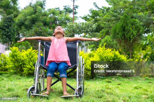 Concept Of Freedom Individuality And Courage Showing By Happy Girl Kid Feeling Nature By Stretching Arms While Using Wheelchair At Hospital Park Stock Photo - Download Image Now