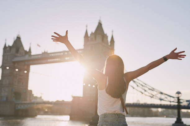 scatto in retrovisione di una donna in piedi accanto al tower bridge di londra al tramonto e che applaude - england uk london england travel foto e immagini stock