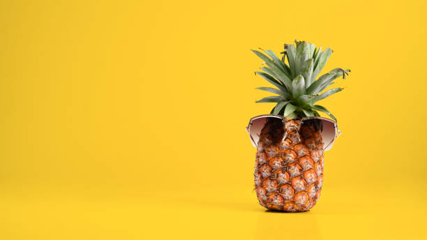 istock Pineapple with sunglasses against yellow background with copy space. Beach and tropical theme. 1395849990