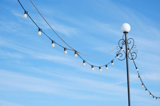 istock Street lamp with hanging bulbs on a blue sky background. 1395852188