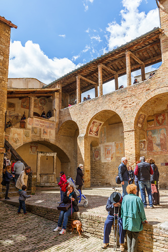San Gemignano, Italy - April 25, 2016: Tourists in a courtyard with old fresco paintings